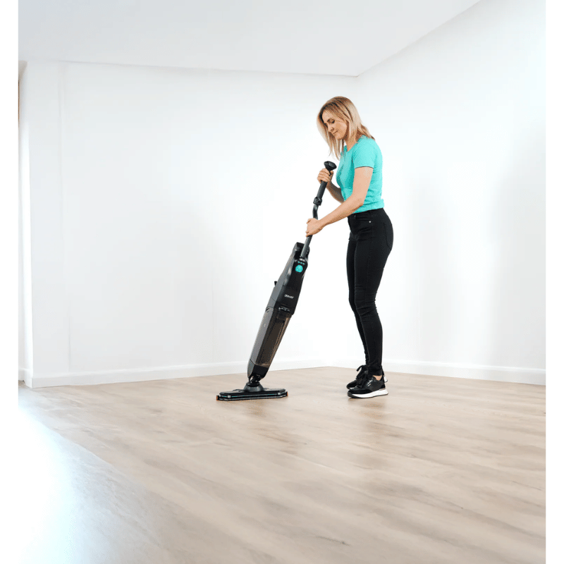 Person using a Cleanstar Dryft Floor scrubber on a wooden floor in a room with white walls.