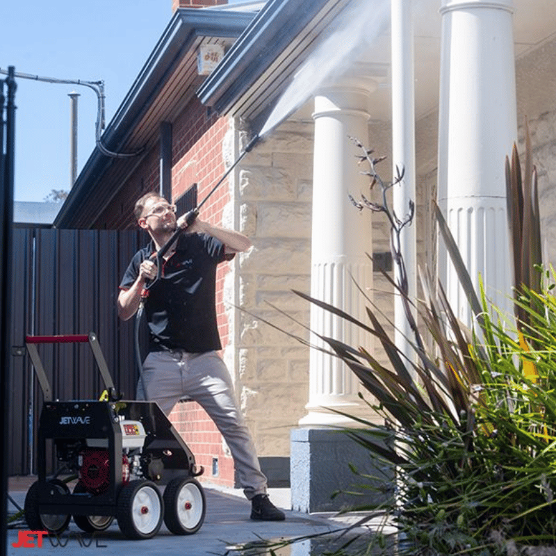 Man using a Jetwave Raptor G2 Jnr 200-11 High Pressure Cleaner outside a house