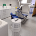 Dental office with a blue patient chair and Rensair air purifier on the floor.