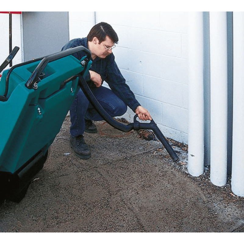 Tennant 3640 Walk Behind Floor Sweeper internal vacuum wand being used by a person to pick up debris