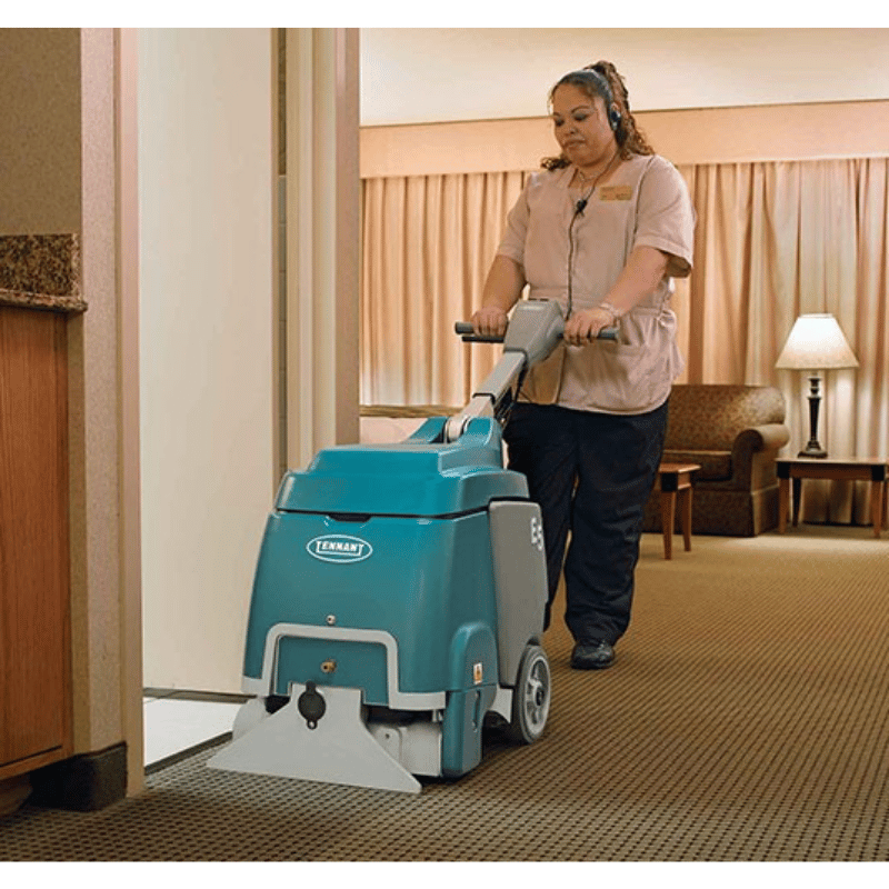 Tennant E5 Compact Walk Behind Carpet Extractor being used by a person in a motel room on carpet floor