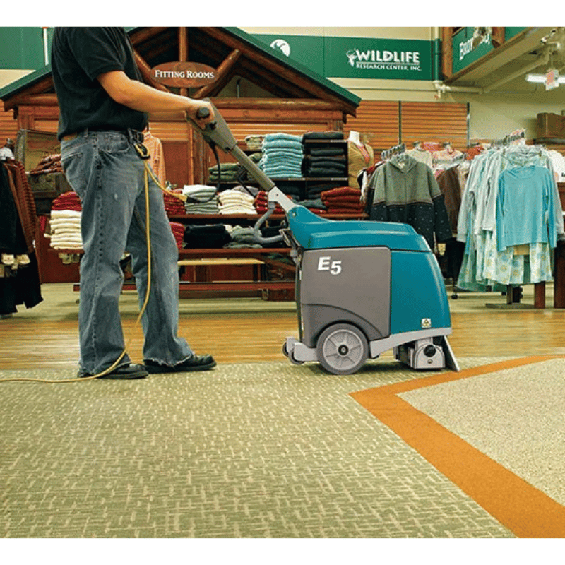 Tennant E5 Compact Walk Behind Carpet Extractor being used in a retail clothing store by a person