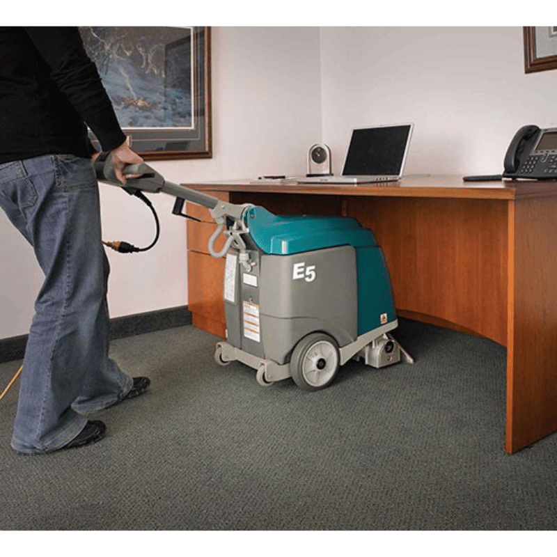 Tennant E5 Compact Carpet Extractor machine being used underneath an office desk 
