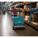 Man operating a Tennant S10 Battery Walk Behind Floor Sweeper in a warehouse setting