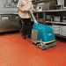 Person using a teal floor cleaning machine in a kitchen setting