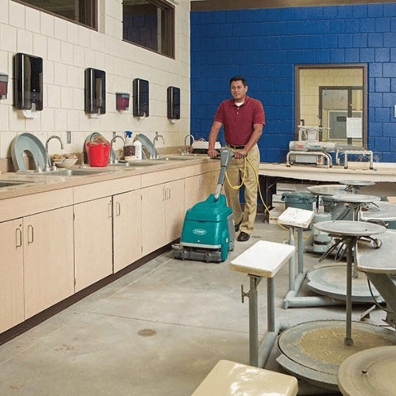 Person using a floor cleaning machine in a classroom setting