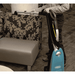Person using a Tennant VSMU36 Upright Vacuum Cleaner on a patterned chair.