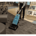 Person using a Tennant VSMU36 Upright Vacuum on a carpeted floor in a store setting.