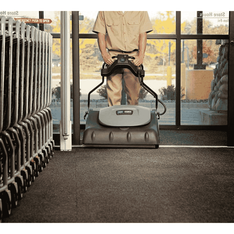 Person using a Tennant VWA76 Wide Area Vacuum in a store with a view of an outdoor area.