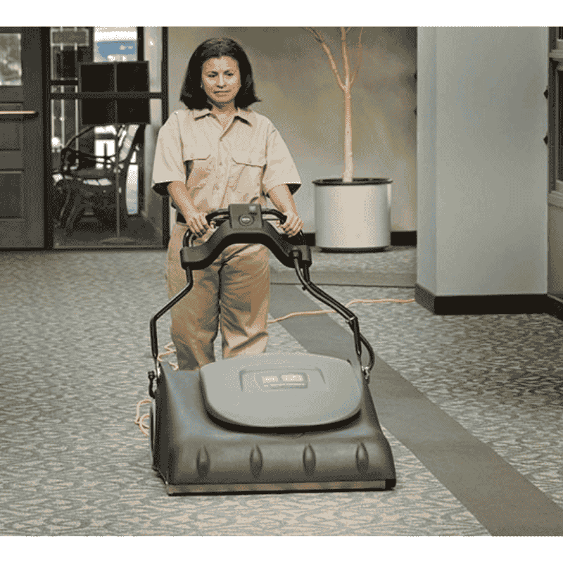 Person using a Tennant VWA76 Wide Area Vacuum in an indoor setting on a carpet area