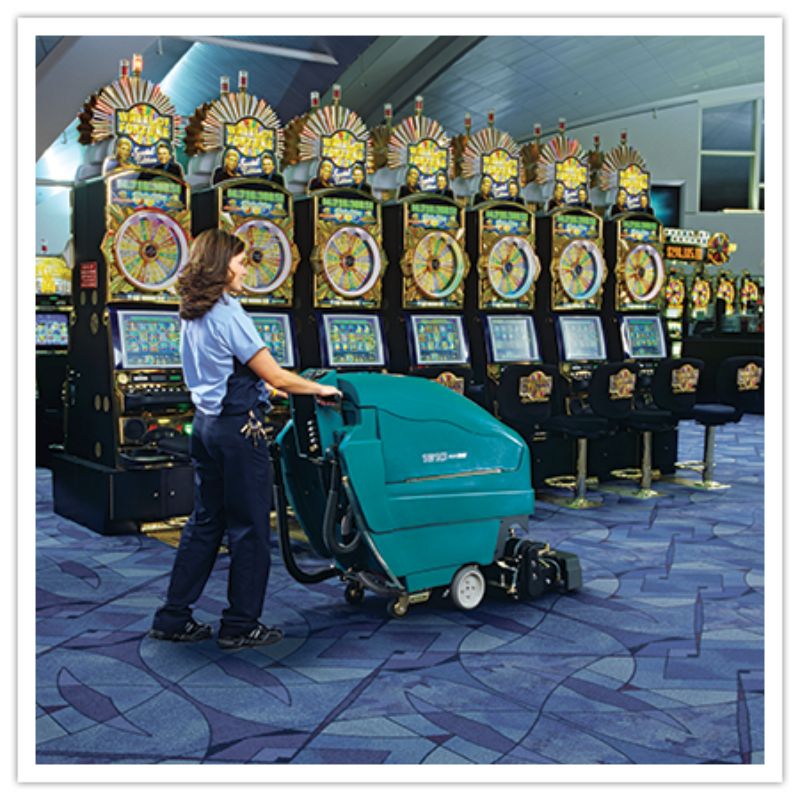 Tennant 1610 ReadySpace Dual Technology Extractor being used by a lady at a casino on blue coloured carpet floor. 