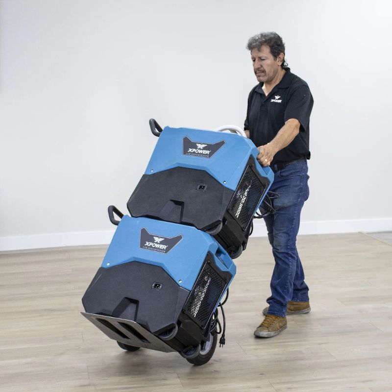 XPOWER XD-85LH Commercial LGR Dehumidifier man is carrying 2 machine in a cart